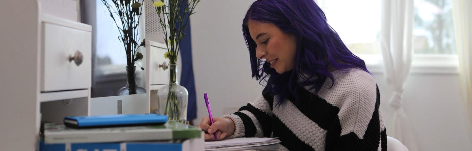 Student taking note while attending to an online class